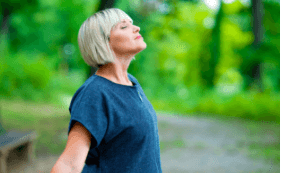 Women standing in the woods taking a deep breath