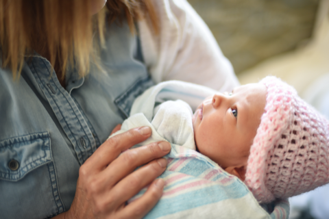 A mother holding a newborn baby in a pink cap