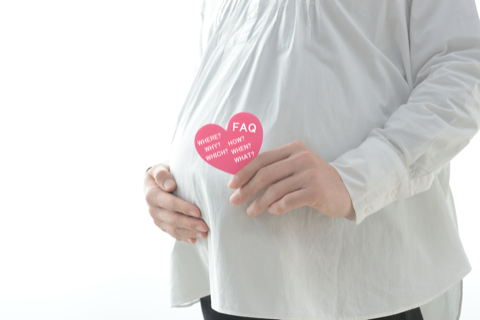 A pregnant woman holding a FAQ note