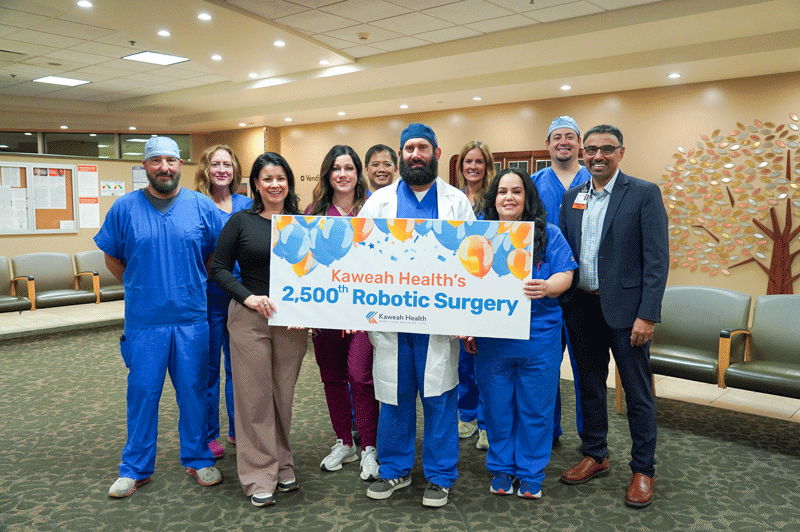 Dr. Ford and his surgery team hold up milestone sign.