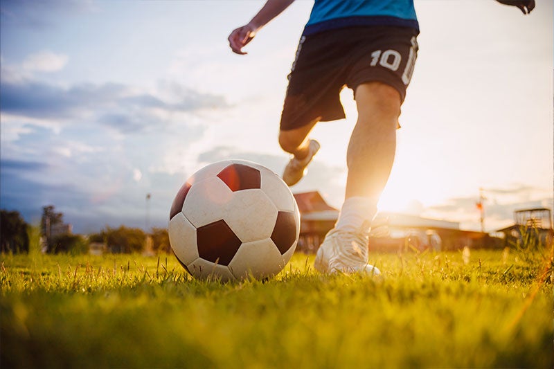 Young soccer player kicking soccerball
