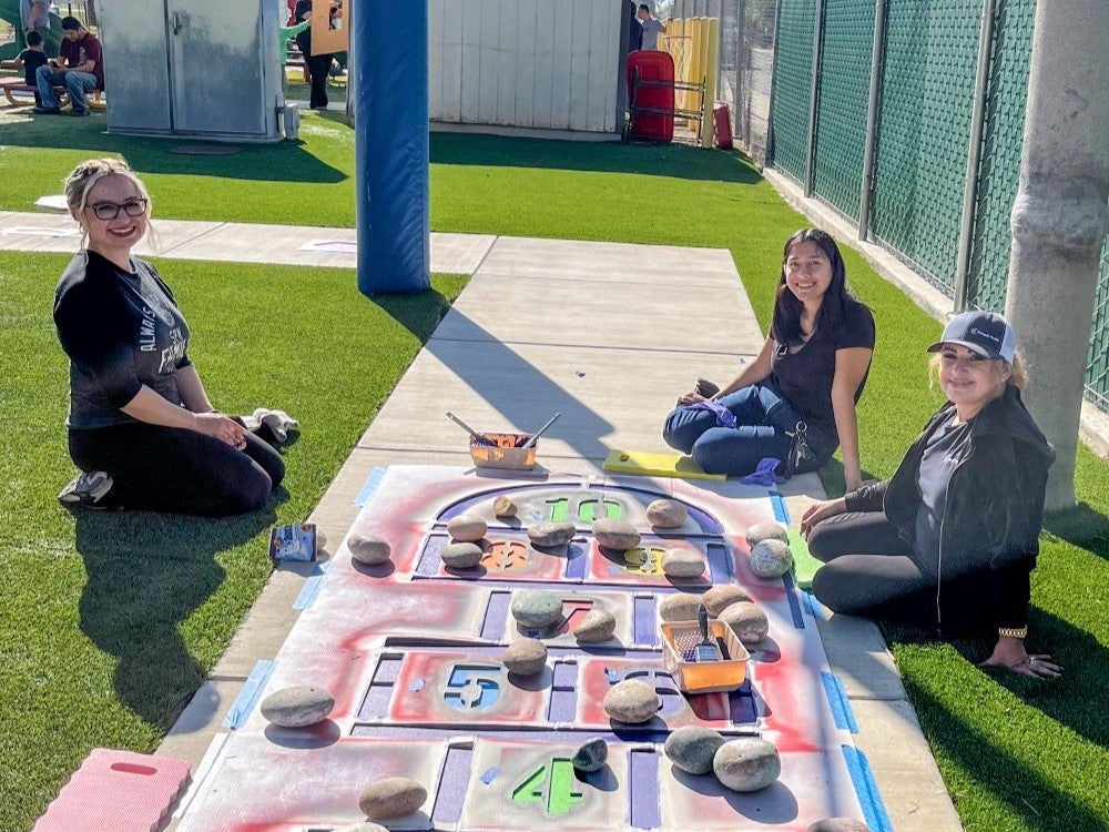 outreach team painting a school sidewalk with learning activities