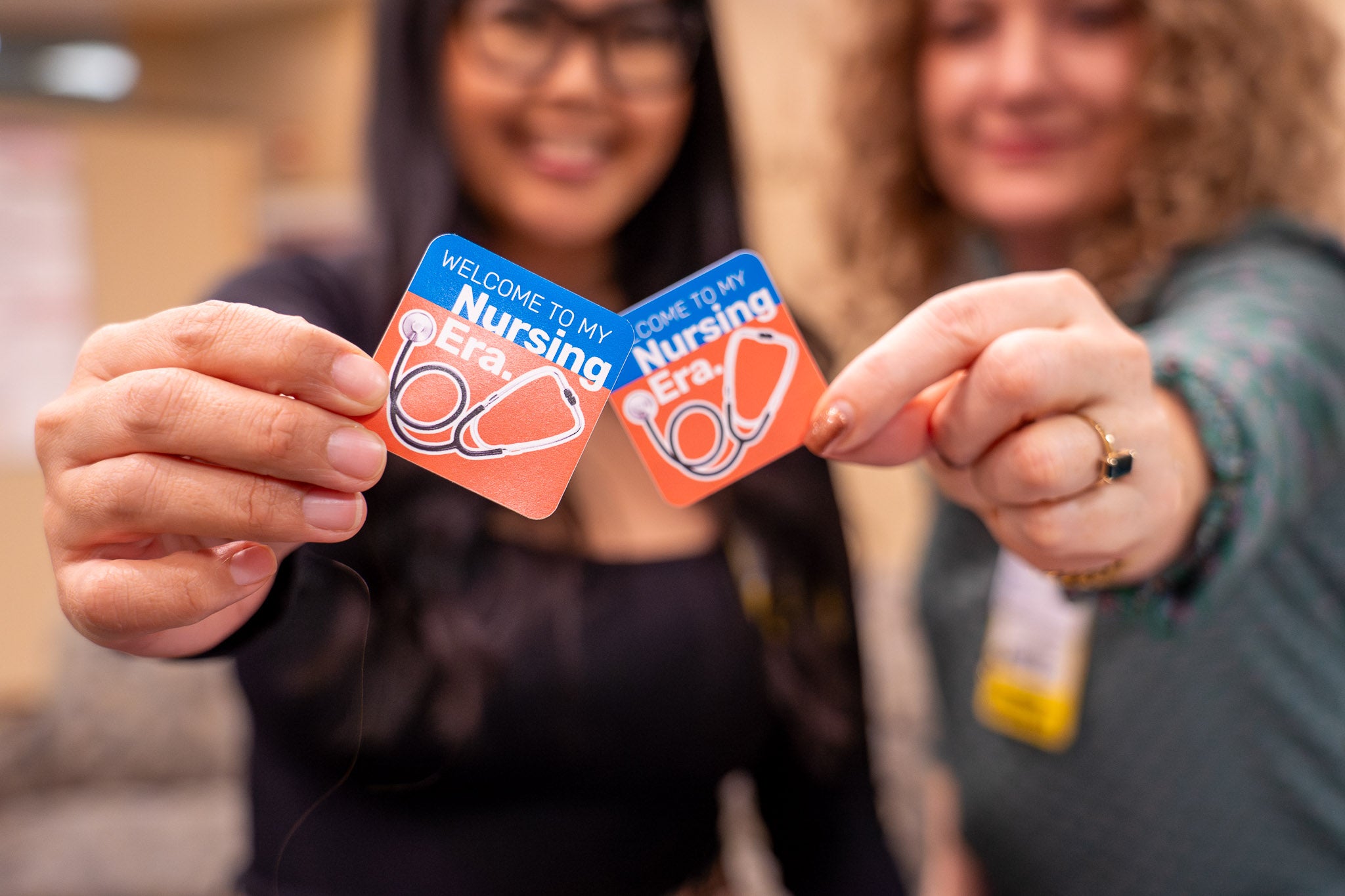 Two nursing recruiters hold stickers declaring "Welcome to My Nursing Era."