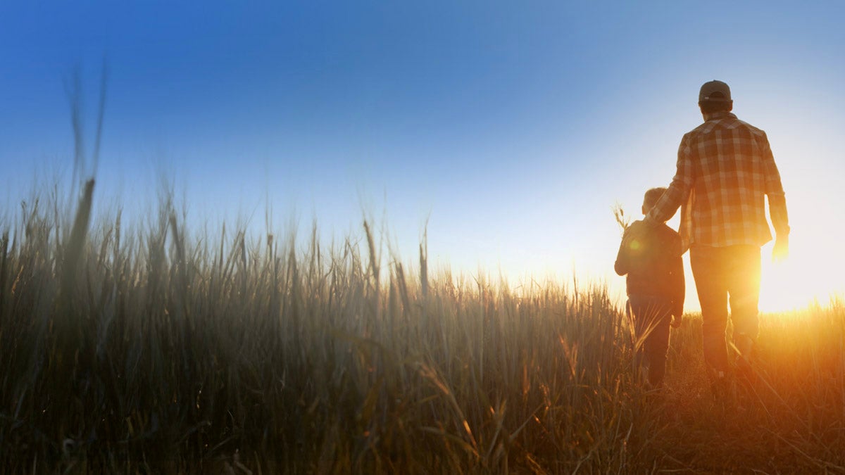 Farmer and child standing in a field.