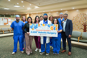 Dr. Ford and his surgery team hold up milestone sign.